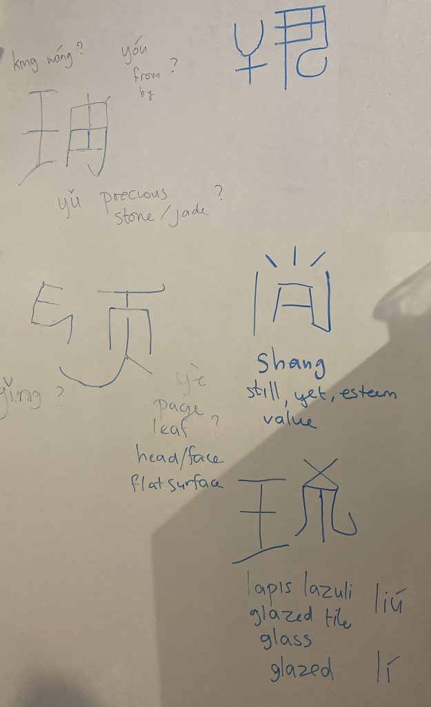 foto van een whiteboard met daarom een aantal slecht getekende Chinese karakters en aantekeningen
